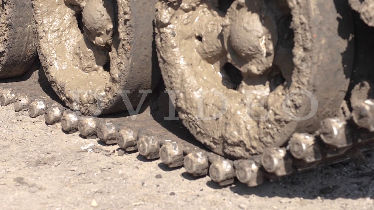 Dirty caterpillar tracks on war tank moving on road slow motion