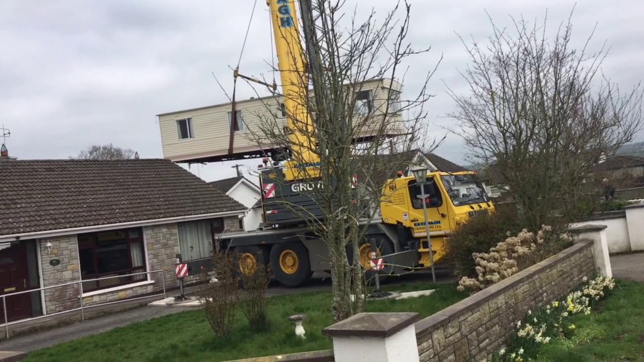 Crane Lifting a mobile home over a house