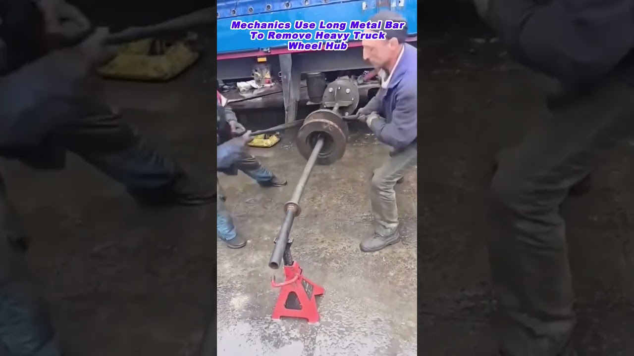 Mechanics Use Long Metal Bar To Remove Heavy Truck Wheel Hub