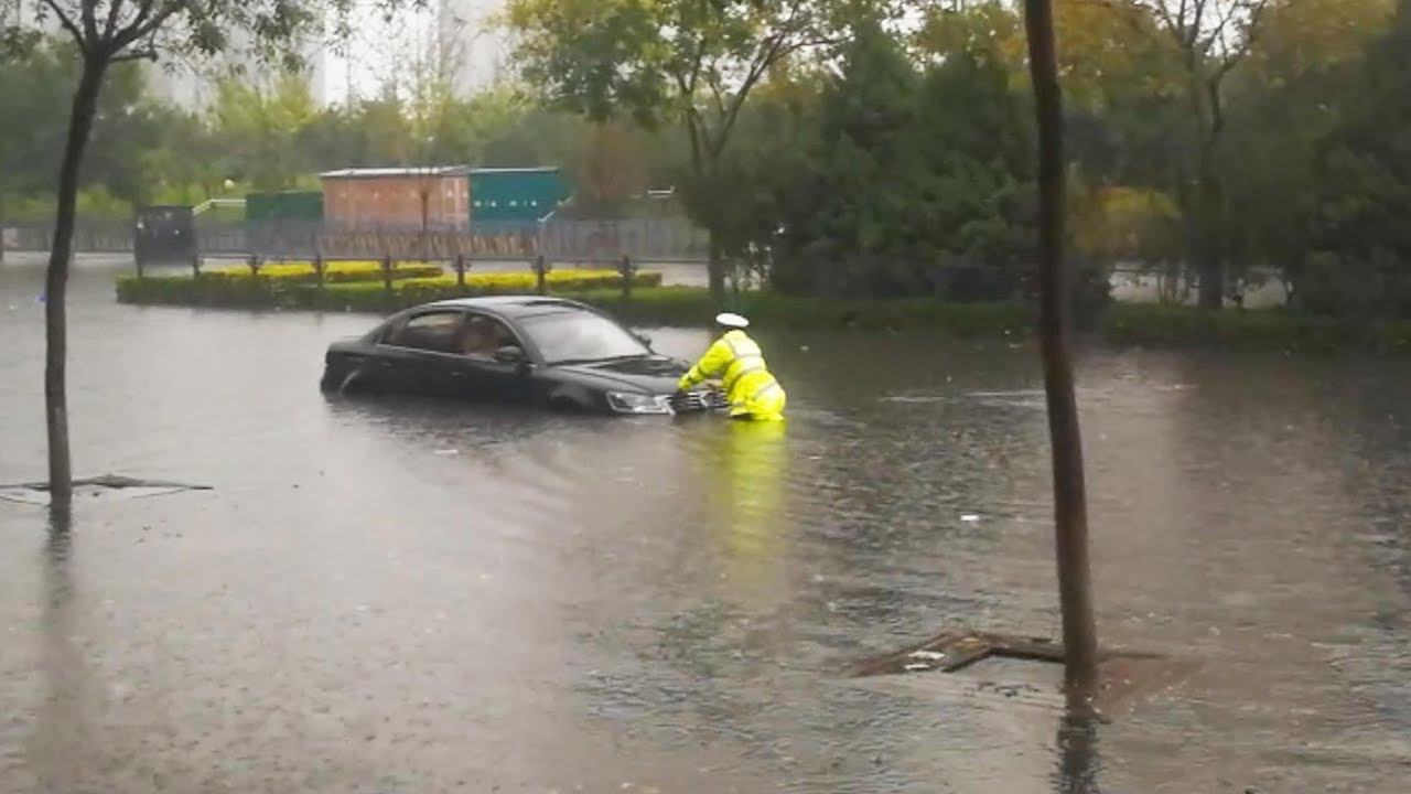 Police officer helps with vehicles trapped in N China's flood