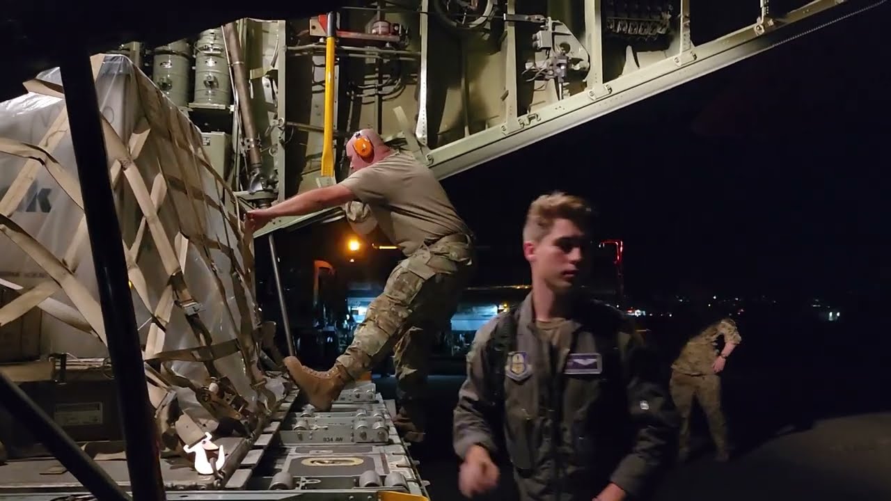 An Air Force Reserve loadmaster and Aerial Port member load a pallet onto a C-130H Hercules