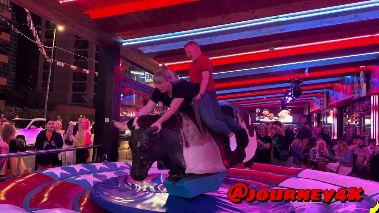 FUN GIRL AND GUY RIDING ON A BULL IN BENIDORM