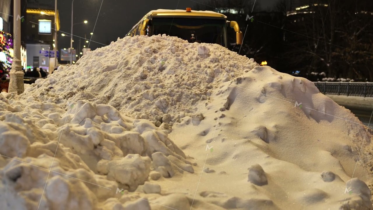 Winter snowdrift blocking city street at night, public transport facing delays