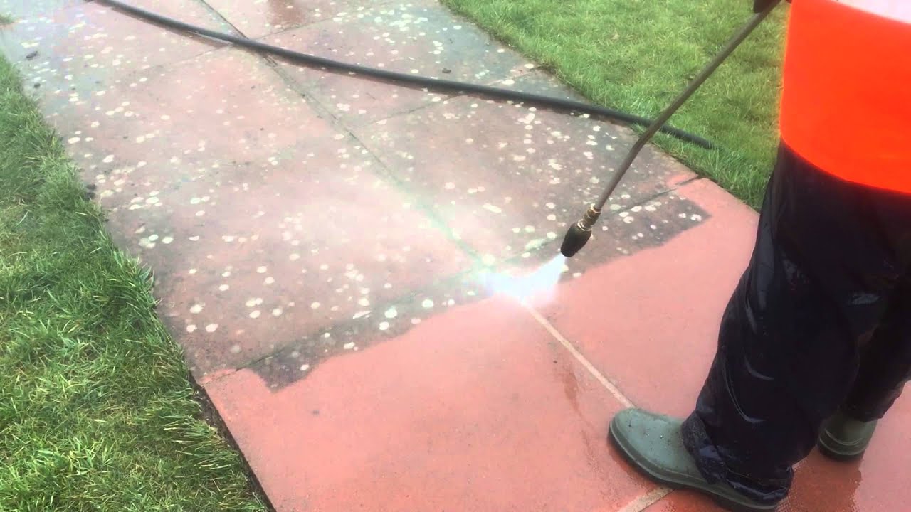 Removing lichen from red paving flags.