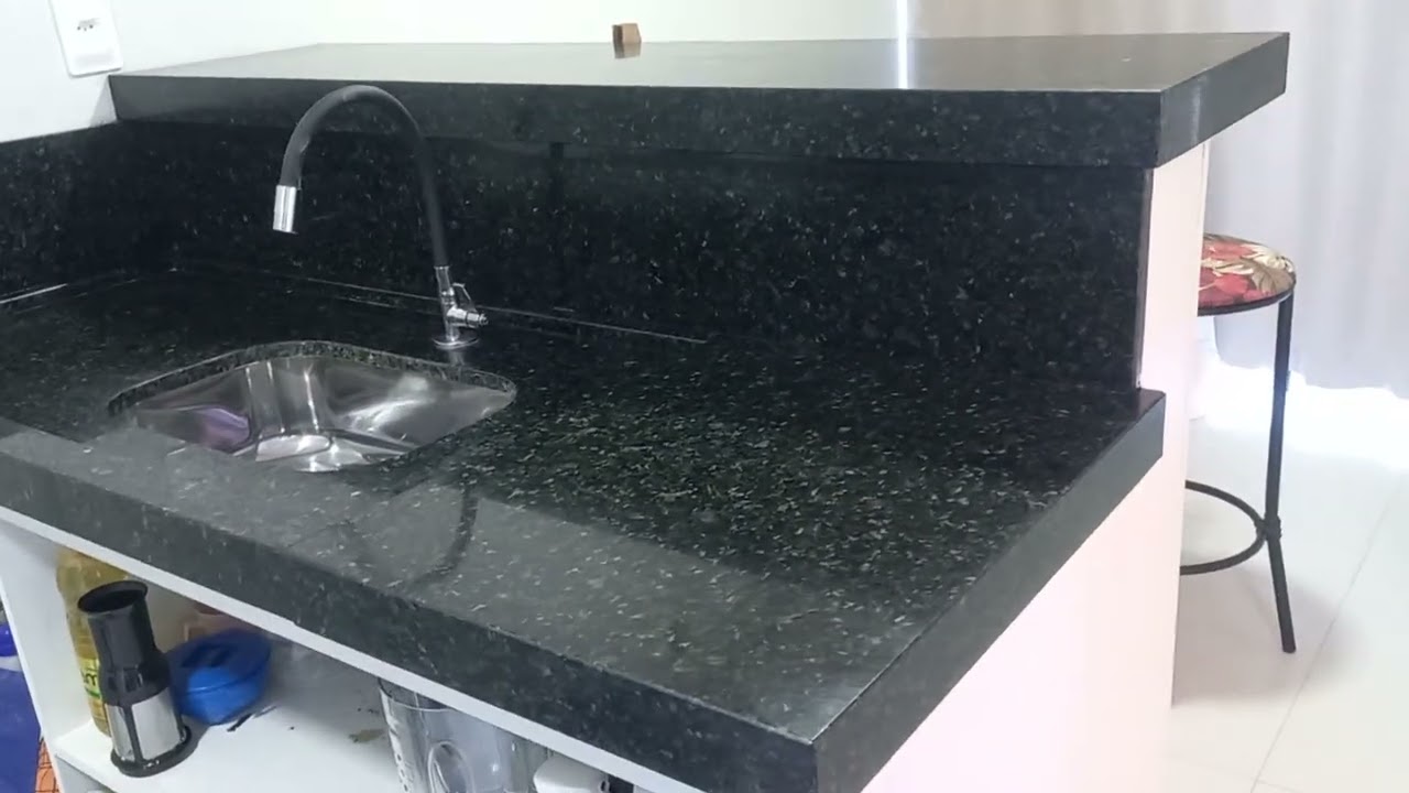 Uma cozinha no granito verde pérola com um balcão. 