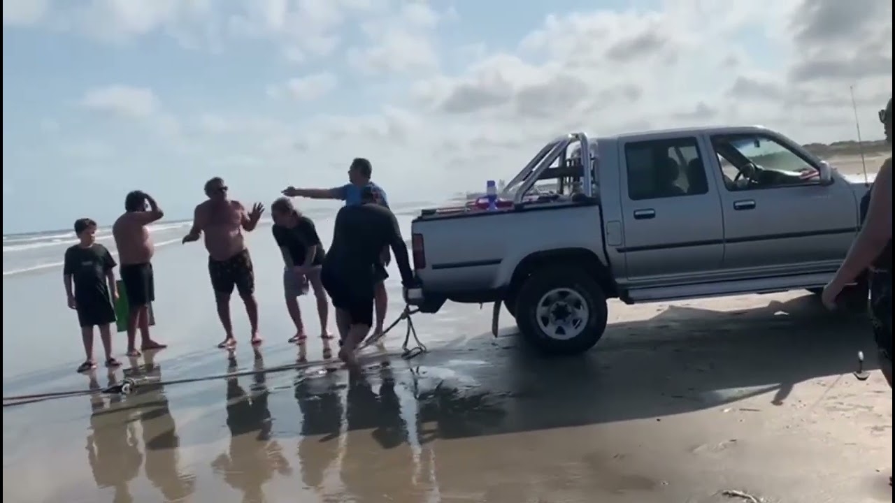 Veículo atolado na praia, maré subindo.