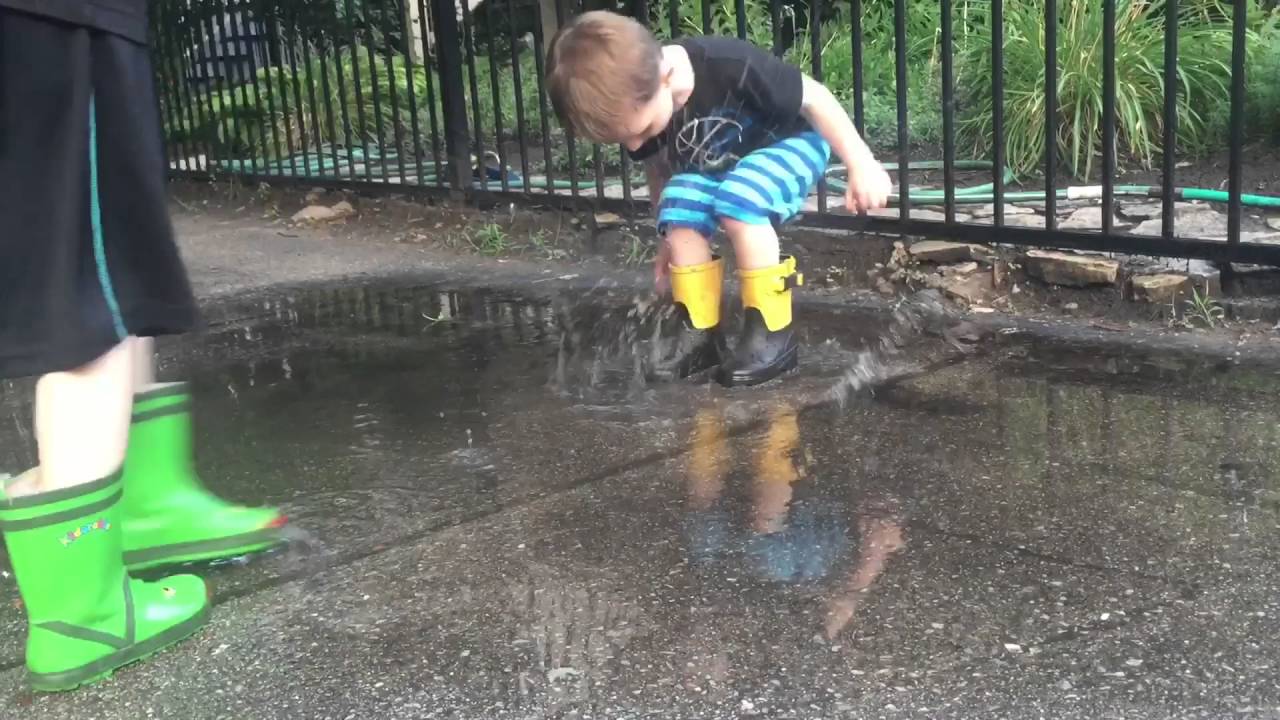 Kids splashing in puddles, in rainboots