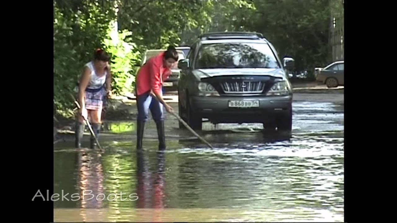 Girls in rubber boots in a puddle looking for the license plate of the car.