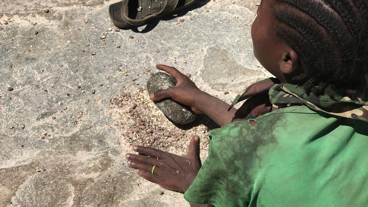 Hadzabe woman pounding baobab seeds to make flour