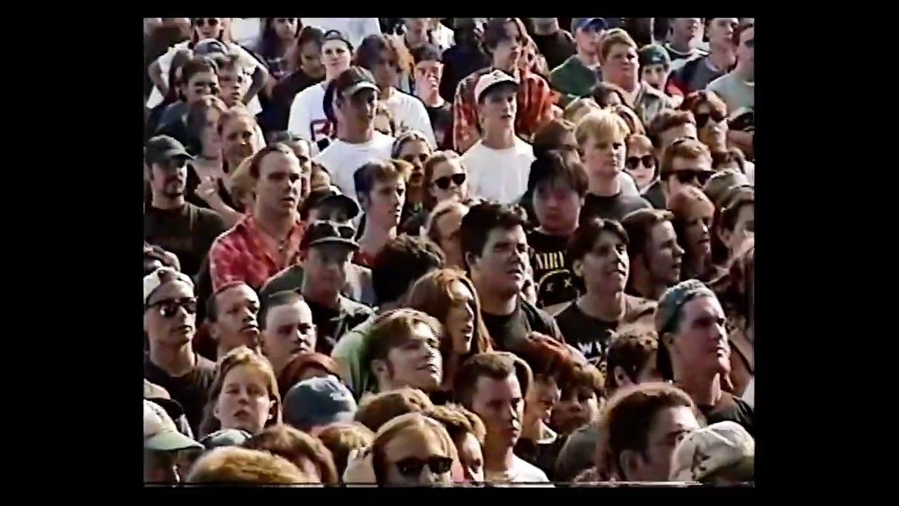 MM playing an outdoor festival. NIN band members sitting on side of stage.