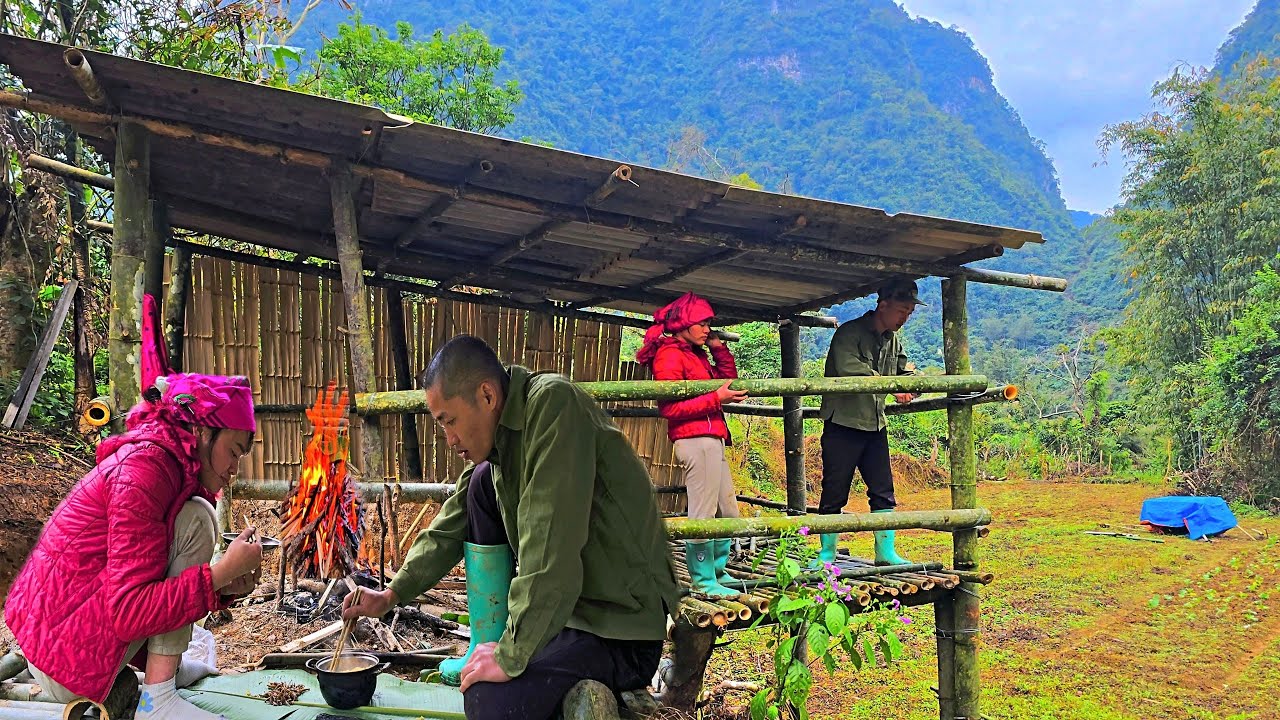 A young couple building a bamboo home & sharing a warm meal in a mountain valley | Mountain couple