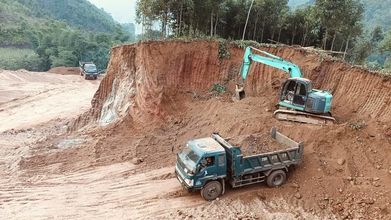 The excavator is loading soil into the truck. 