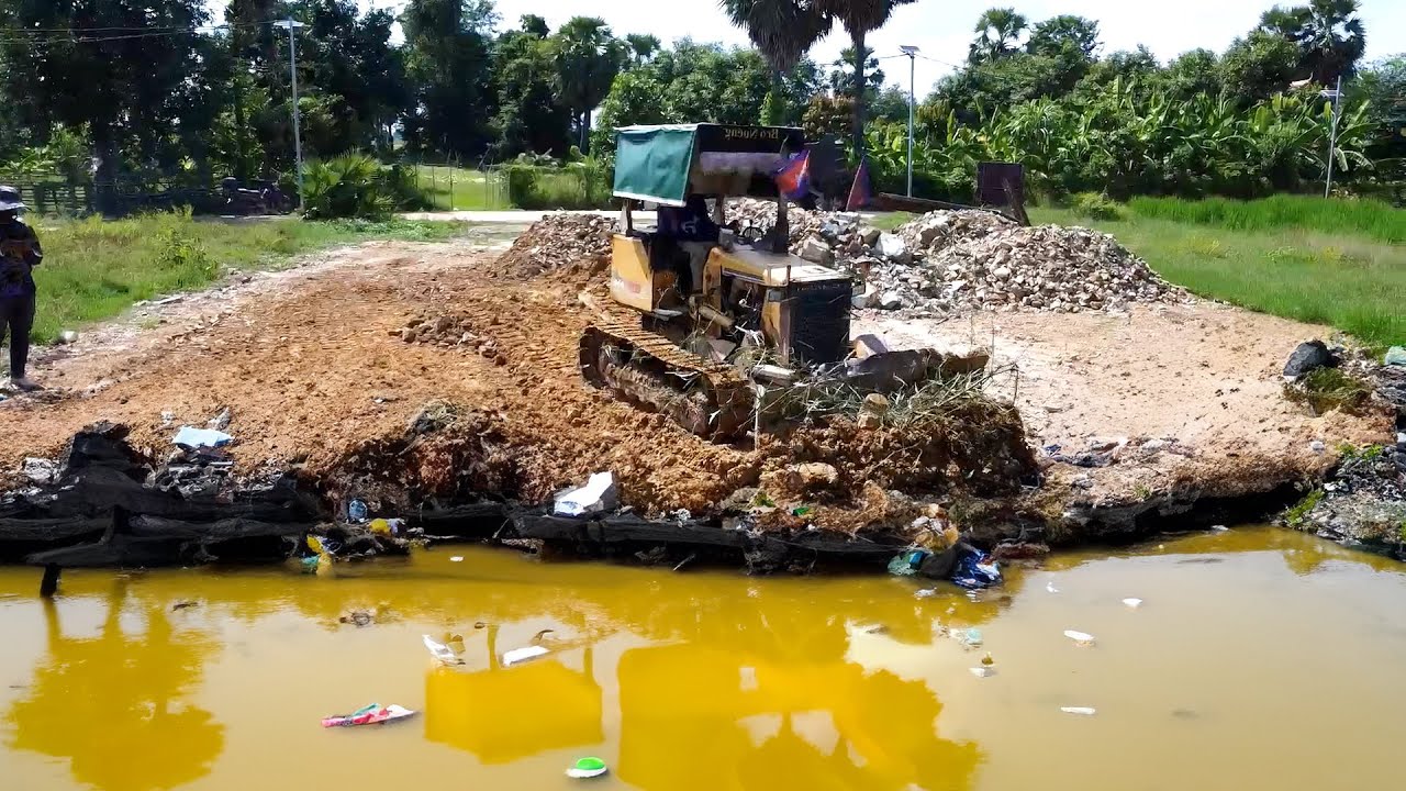 Bulldozer action begins pushing rocks into the water to scare people away.