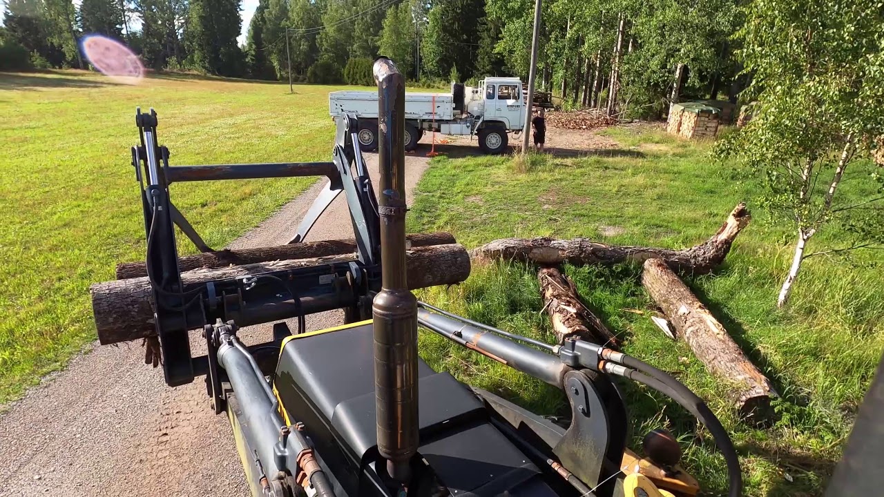 Volvo BM 6300 loading large firewood onto truck using grapple