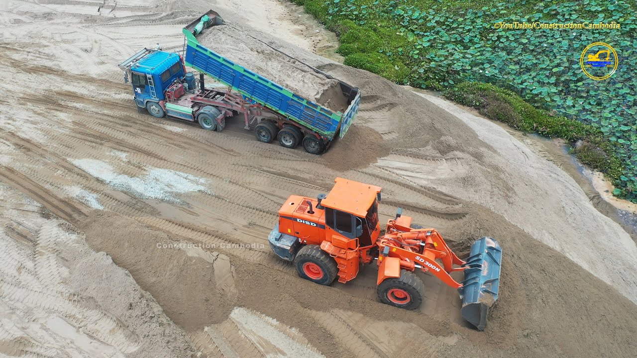 Tipper trailer truck unloading sand and wheel loader moving sand - sand construction machinery work