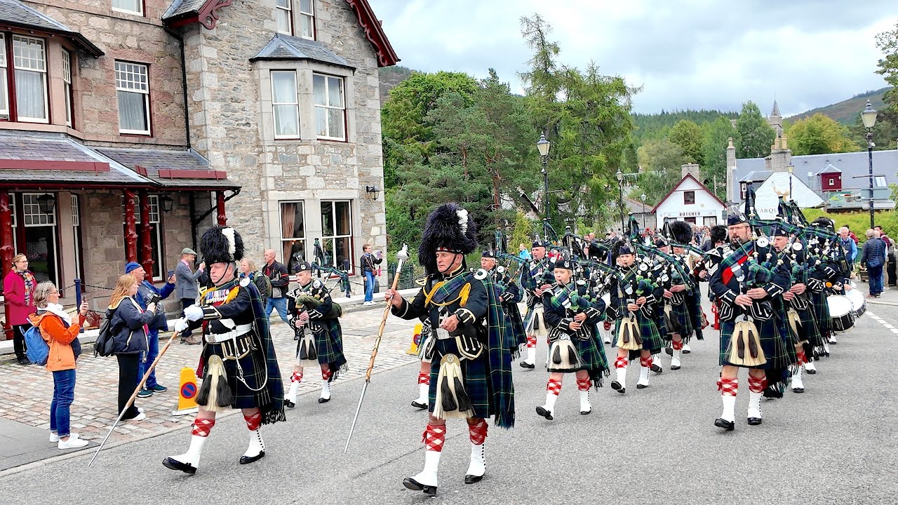 Drum Majors lead the Lonach Pipe Band march through village to 2025 Braemar Gathering in Scotland