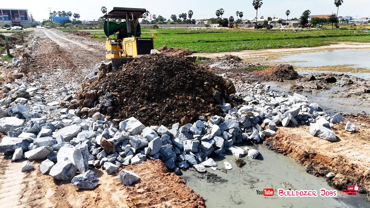 Skilled Komatsu D31P Bulldozer Cutting New Road Through Deep Mud & Trucks Filling Stone Base