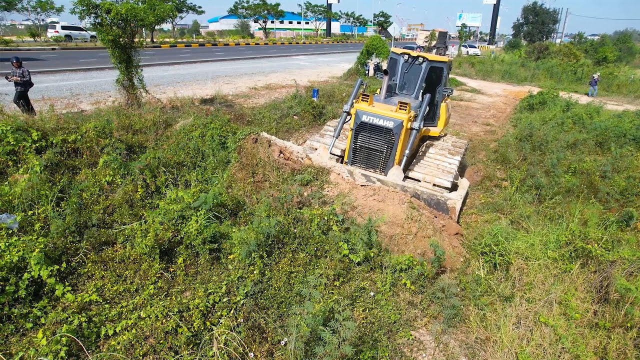 A powerful dozer clears the land and while dump truck loads transport material
