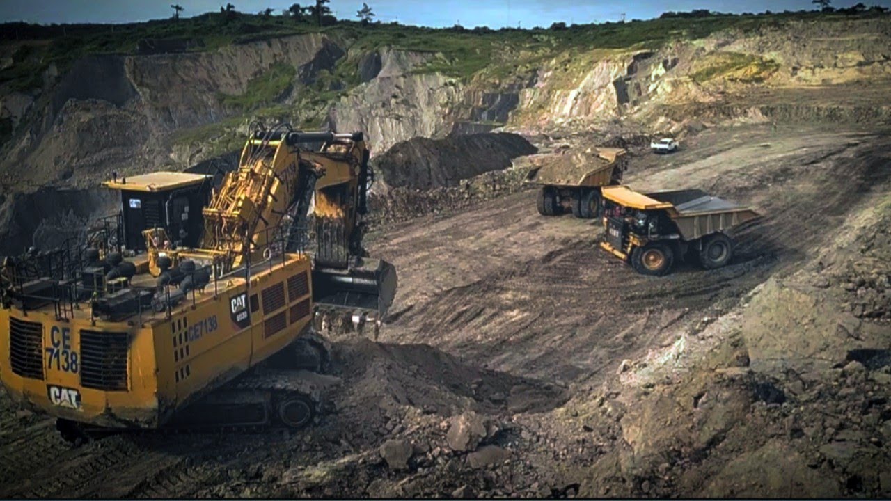 Truk oleng memuat pasir di excavator raksasa caterpillar 6030