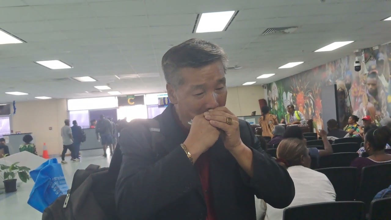 Mouth Organist Pesta King Performs for Bored Passengers at Jackson's Airport Departure Lounge.