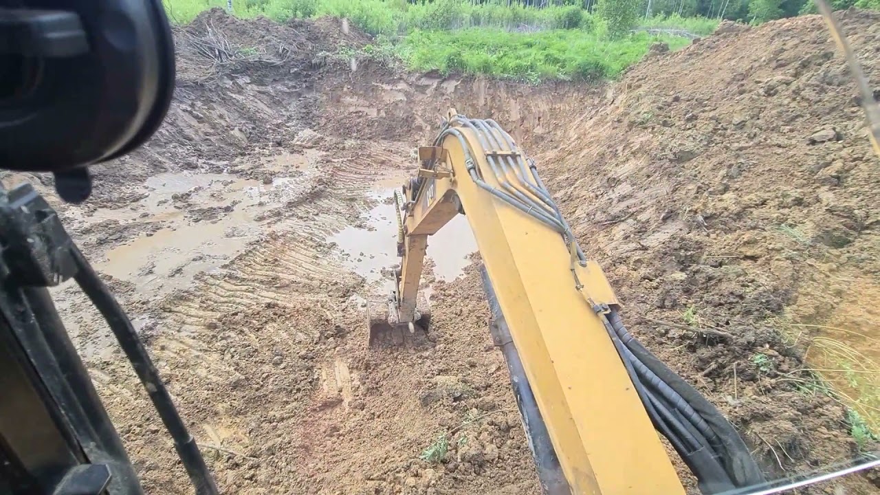 Миниэкскаватор CATERPILLAR копает озеро