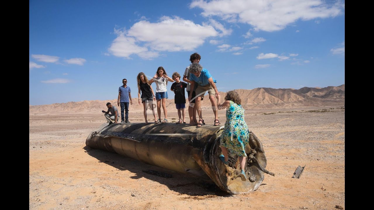 People take their photos with debris of intercepted Iranian missile in southern Israel