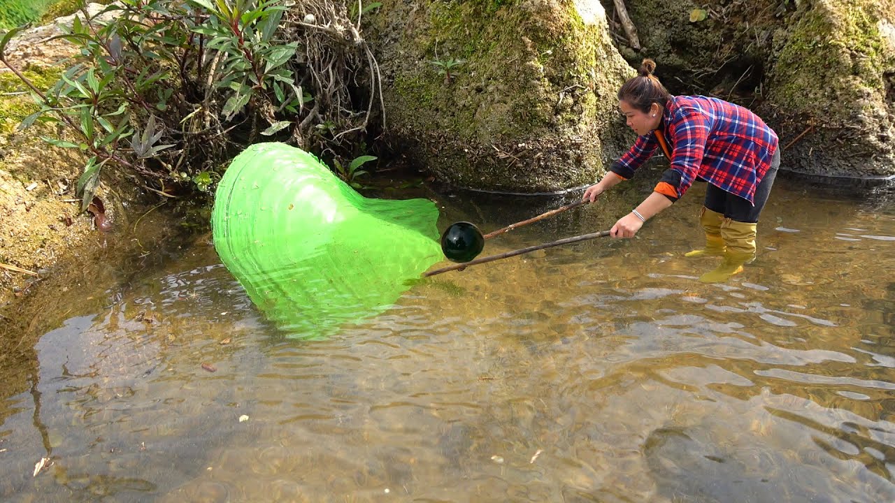 This woman found a huge green clam, it's too heavy. She picked up the pearl with two sticks