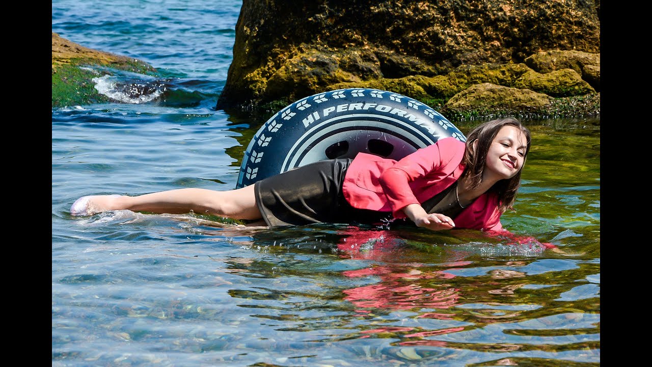cute girl after work in the office in wet clothes swims on an inflatable ring in the sea
