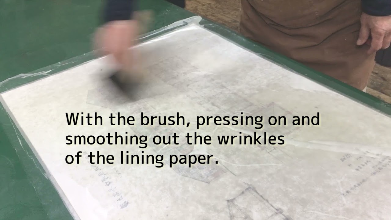 Applying the lining paper to the back of the artwork