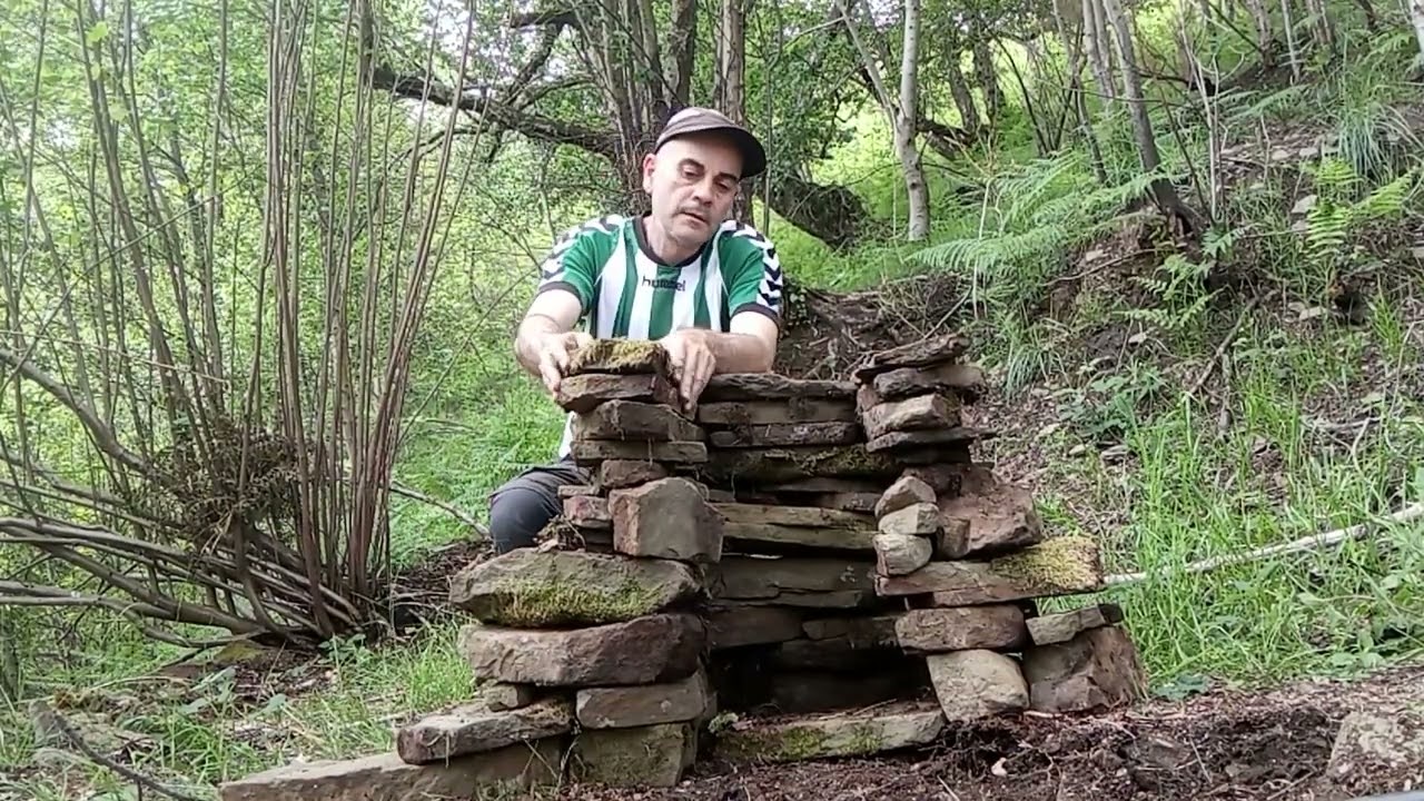 Refugio de supervivencia con toldo(tarp) y chimenea de piedra