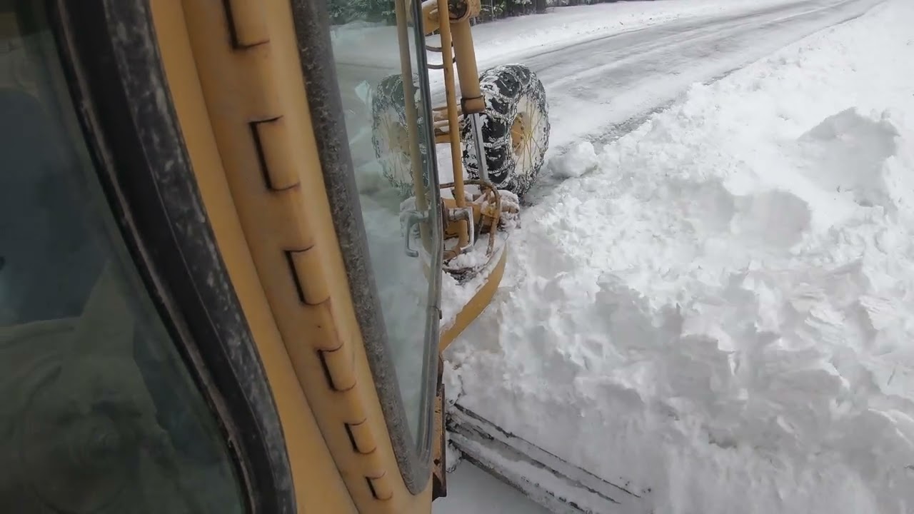 grader plowing snow and pushing back snow berms