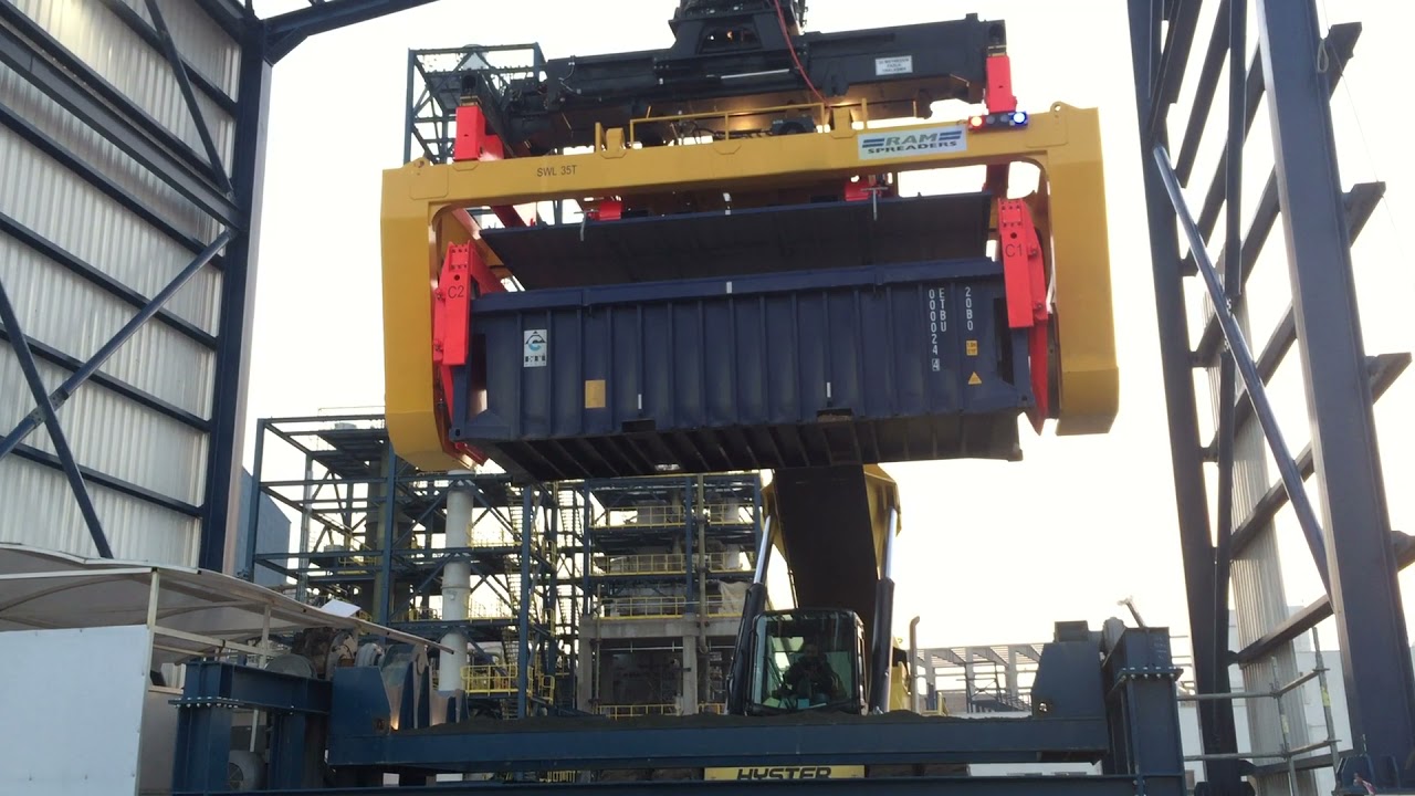 Rotating spreader on Reach Stacker unloading bulk into hopper