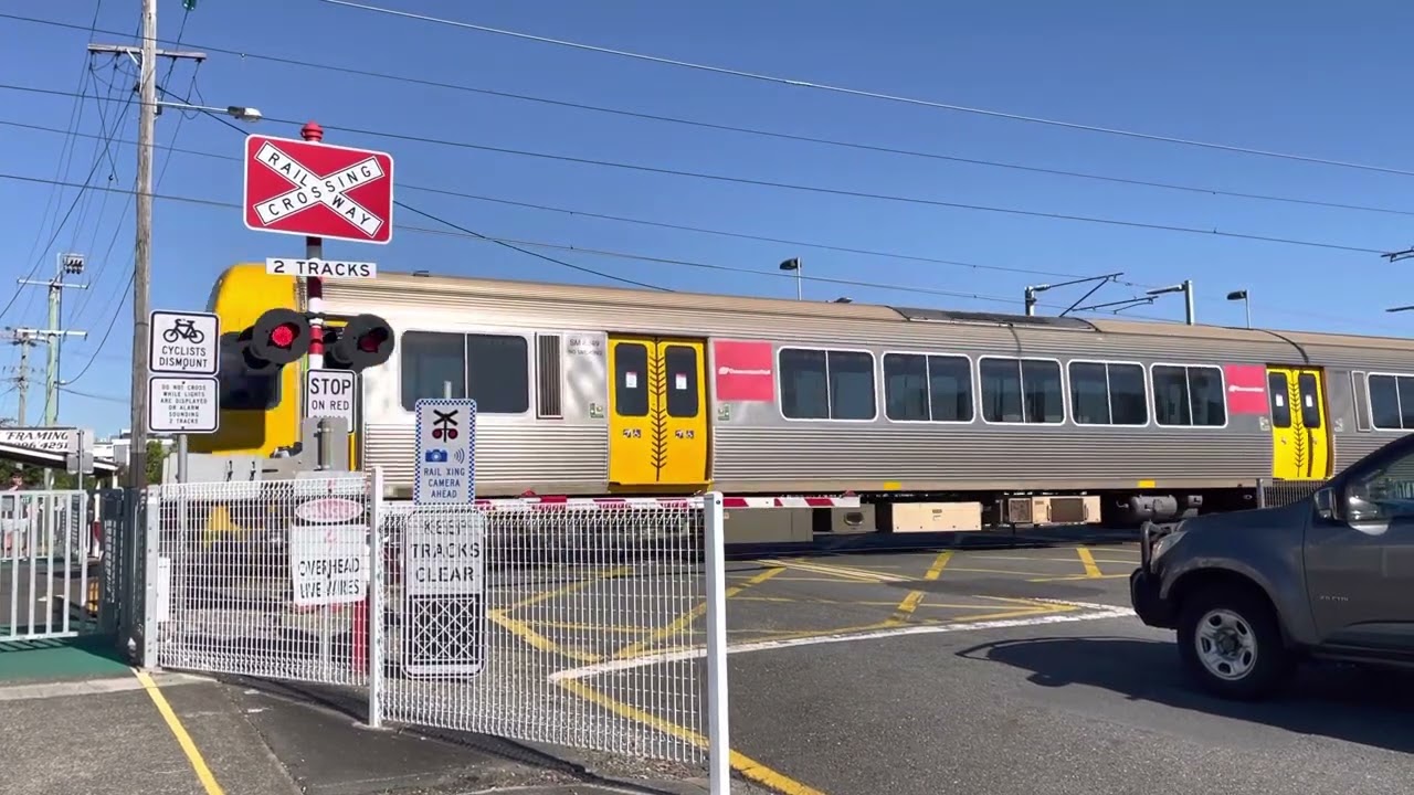 Boom gate level crossing Wynnum Central and two trains passing through