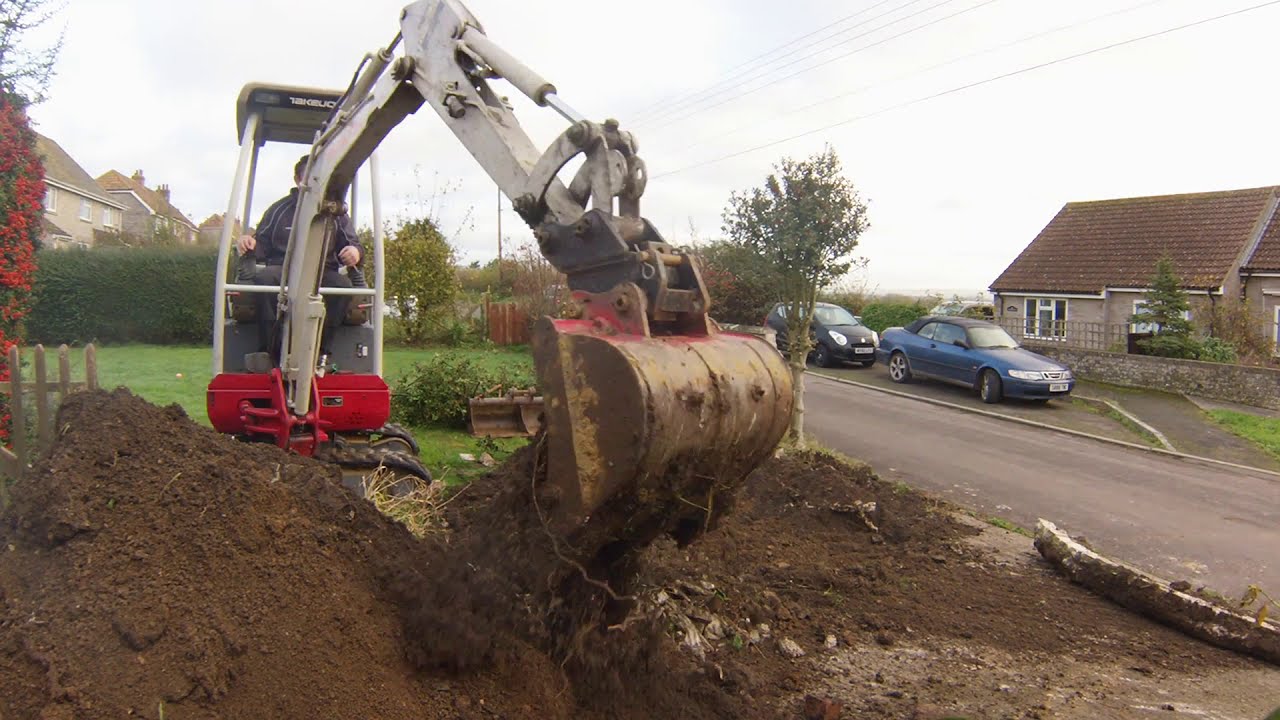 Digging out a driveway with a mini digger Takeuchi excavator