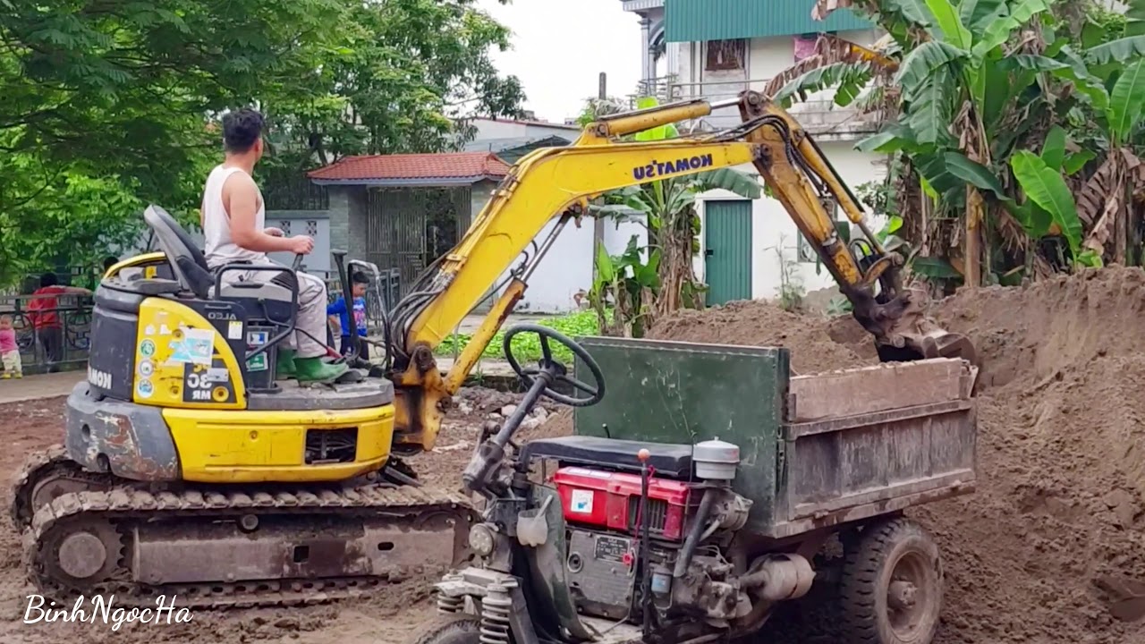 Komatsu MR30 excavator scoops sand onto three-wheeled tractor, Weird car