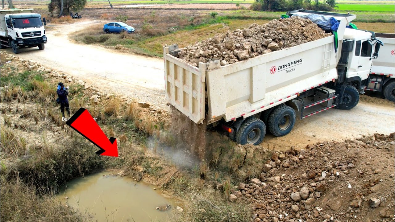 Wonderful Heavy dump truck Dong Feng unloading soil landfilling flooded with SHANTUI Dozer pushing.