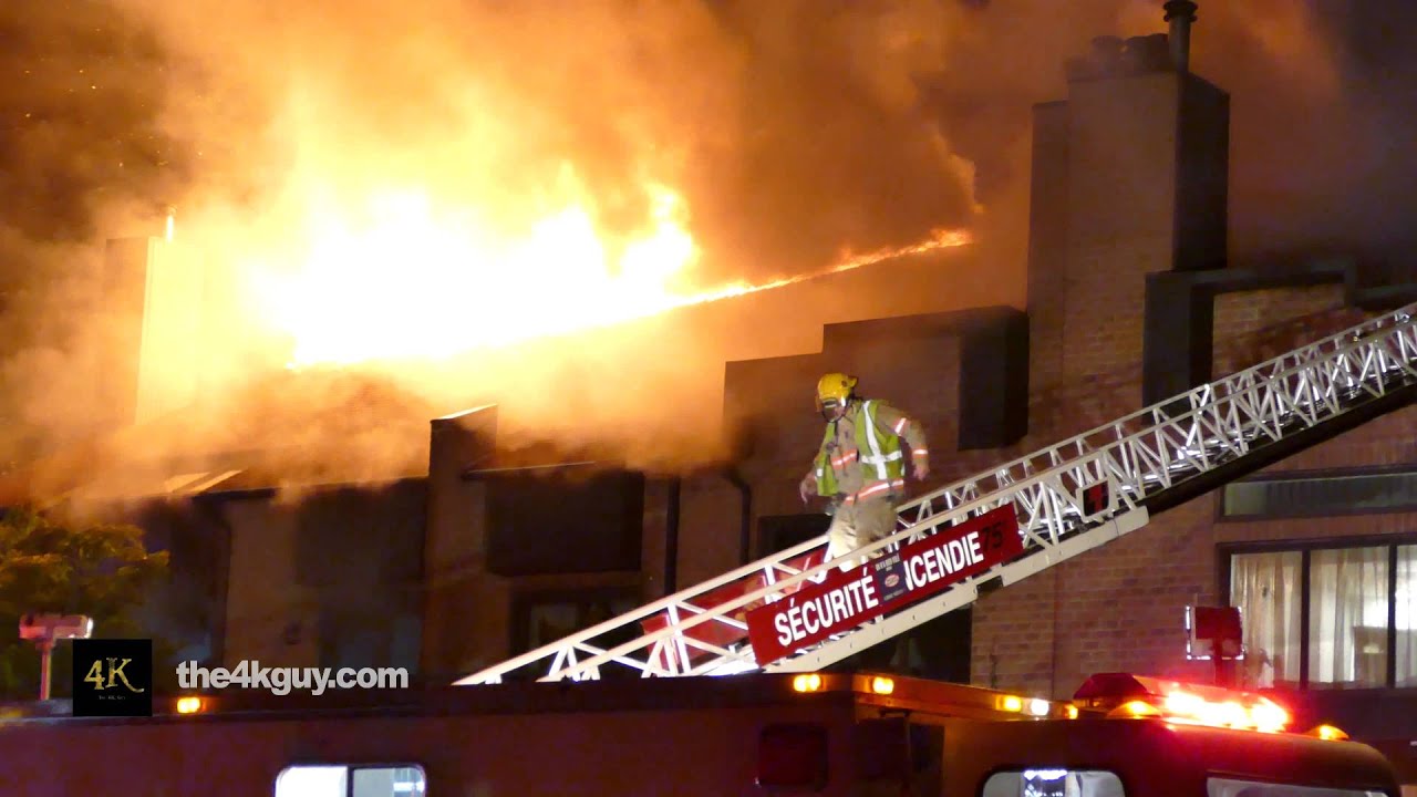 4K UHD - Fire fighter walking down ladder with huge flames in background