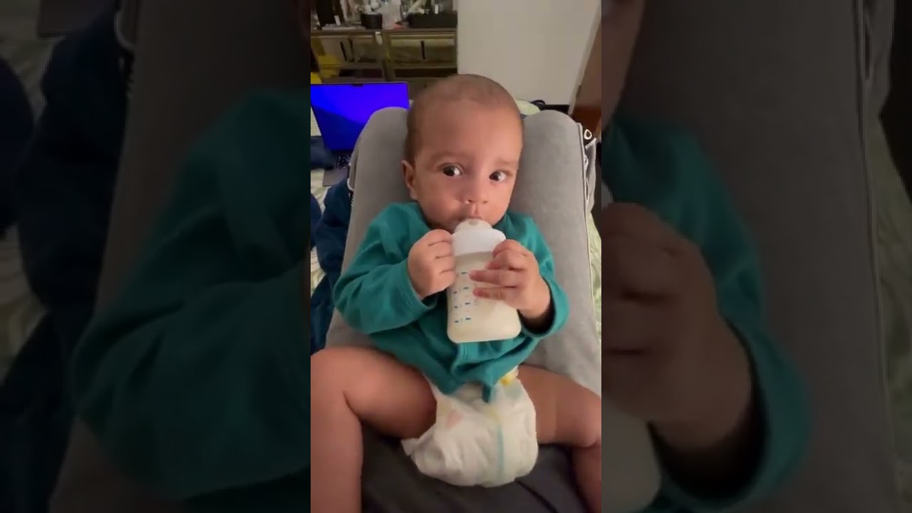 baby holding bottle and drinking milk