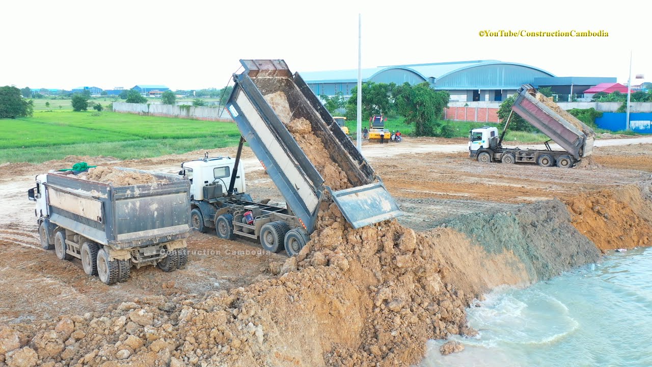 Scania dump truck unloading dirt and Shantui bulldozer pushing dirt