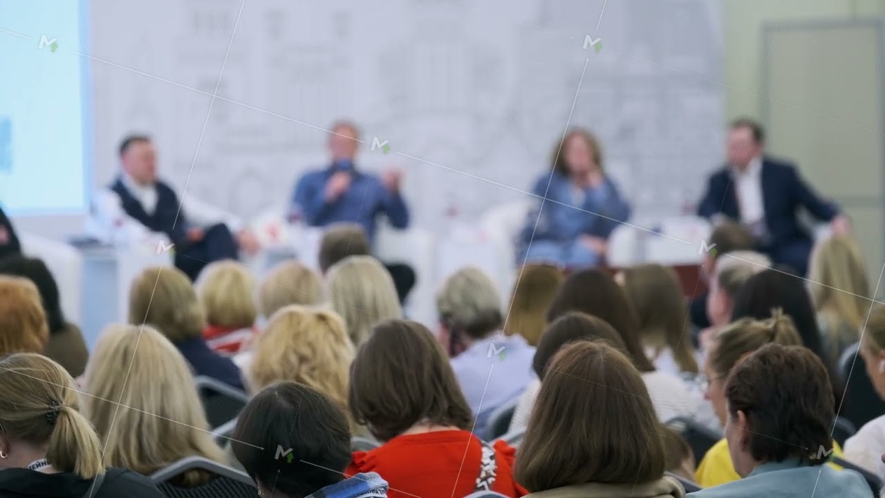 Group attending panel discussion at a business event with multiple speakers