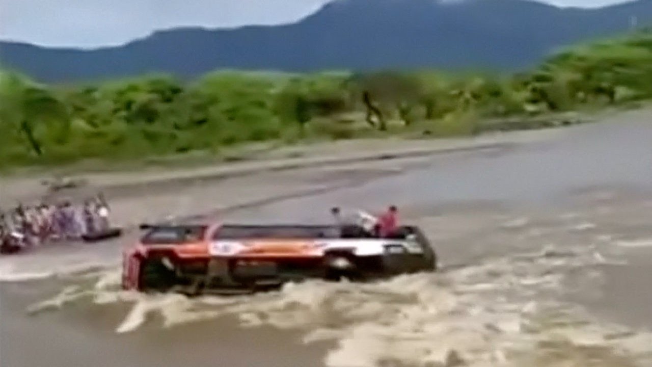 Footage: Passengers trapped after bus overturns into swollen river in Peru