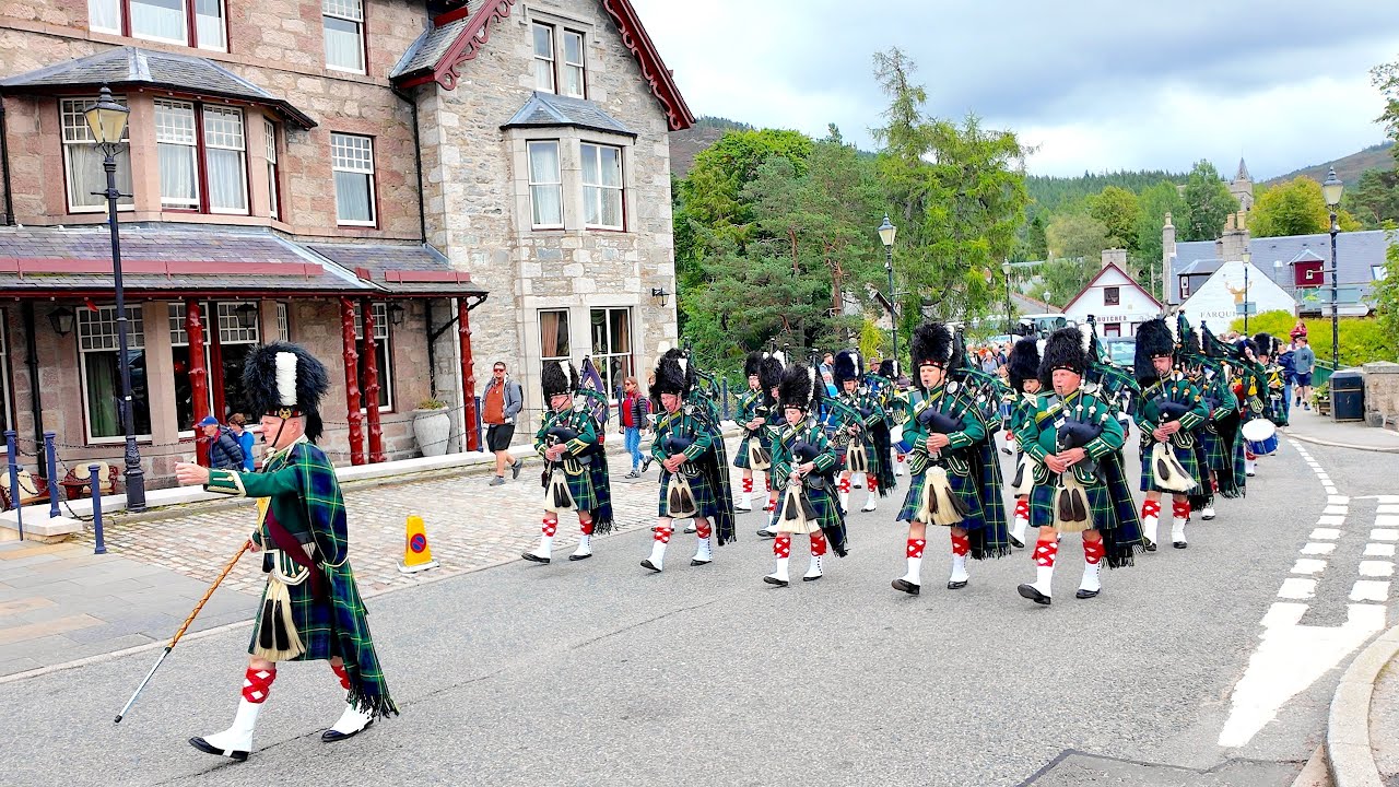 Drum Major leads Huntly Pipe Band playing Scotland the Brave on the march to 2025 Braemar Gathering