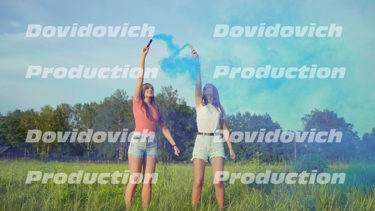 Two happy girls spray blue smoke and make a heart shape out of it.