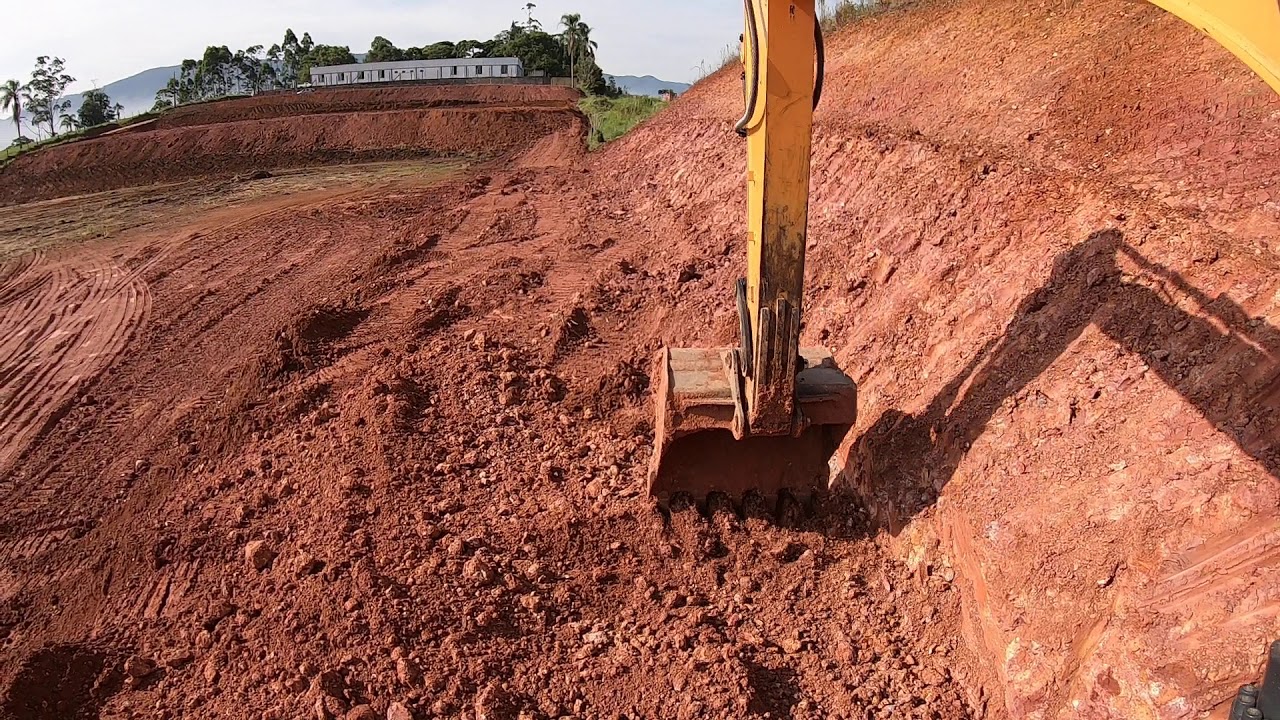 Escavadeira hidraulica finalizando rampa riscada visão externa operador capixaba
