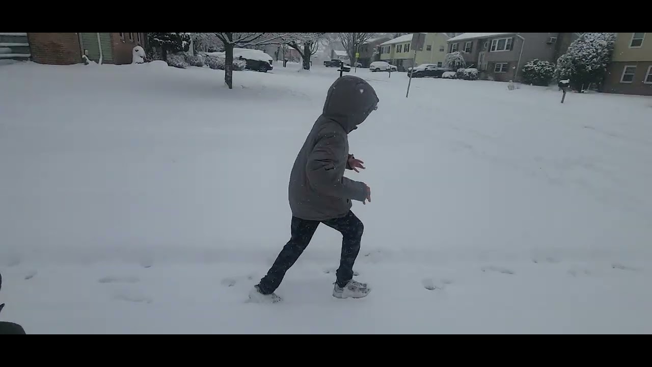 My little brother playing with the snow . 