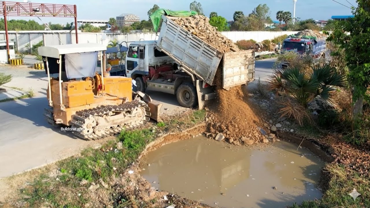 New project Landfill by Bulldozer Komatsu d31P working push soil and dump truck unloading soil fill.