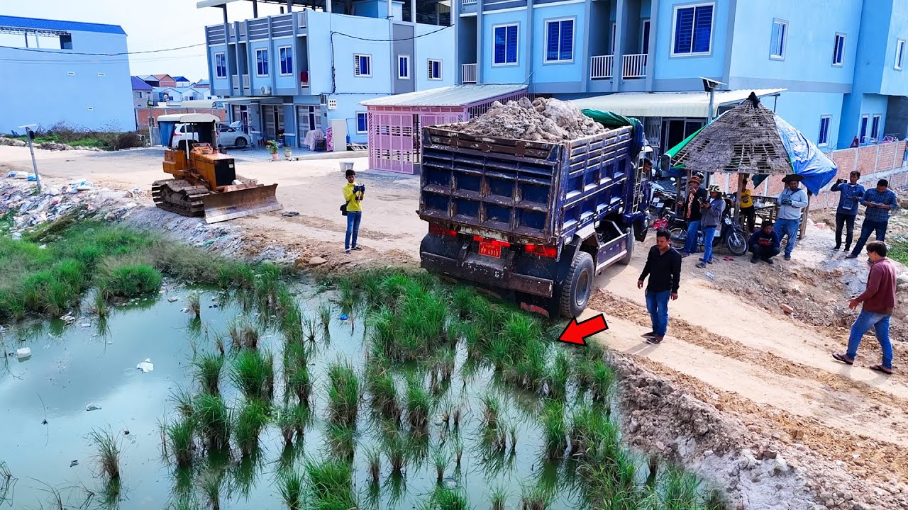 Nice Bulldozer starts filling new project with dump trucks