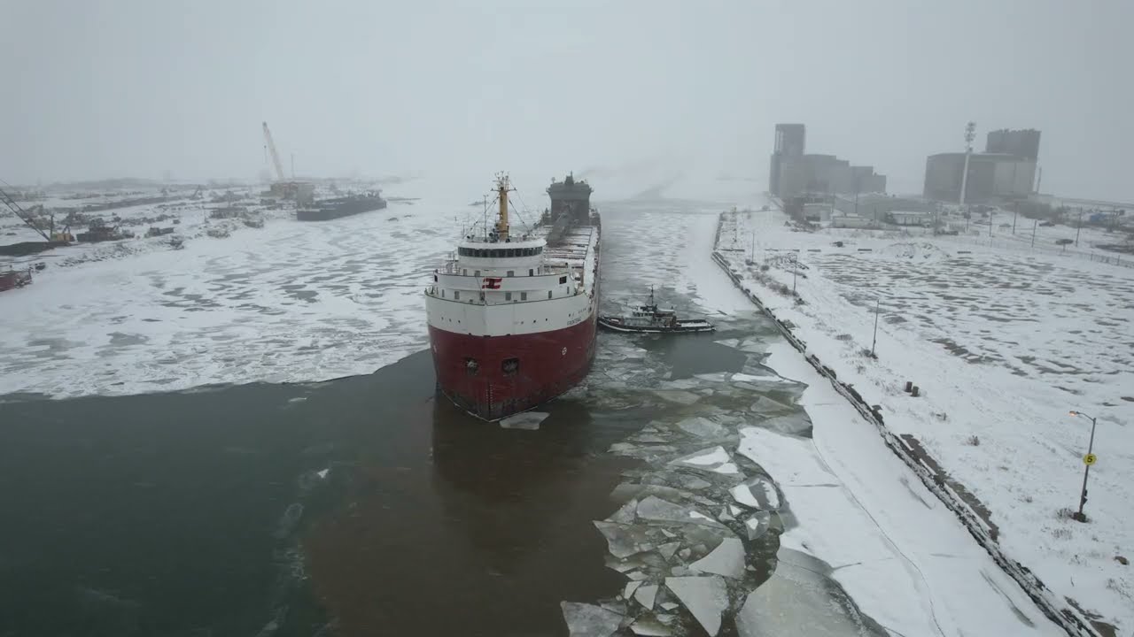 U.S. Coast Guard and tug boat break CSL Frontenac out of its berth in the frozen Welland Canal