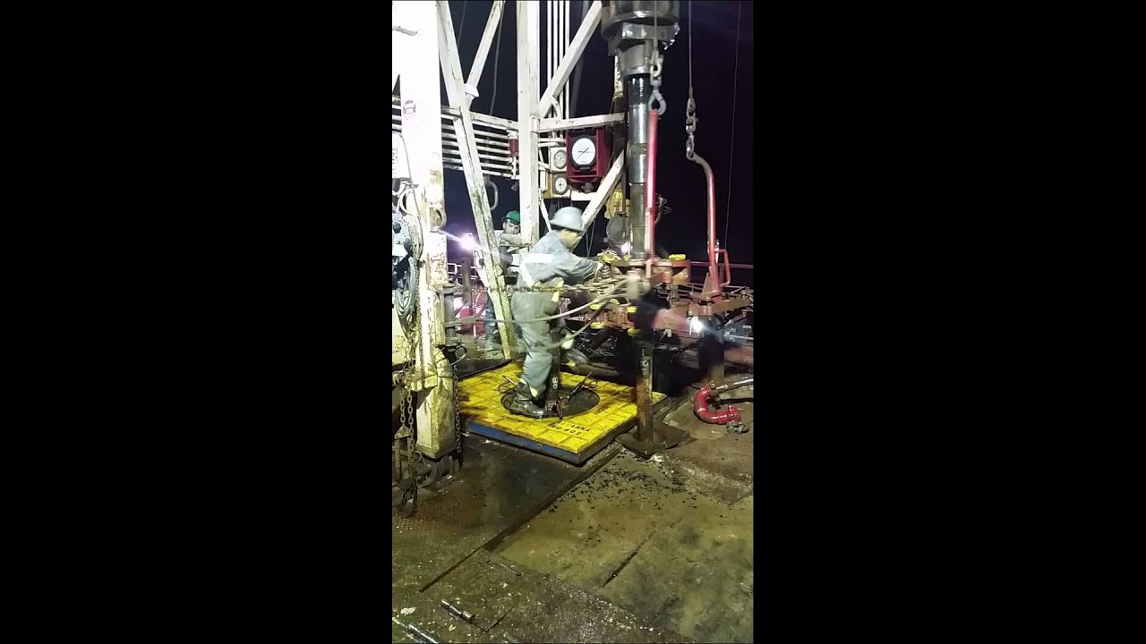 Iron roughneck - hand throwing tongs on a double kelly rig in west texas