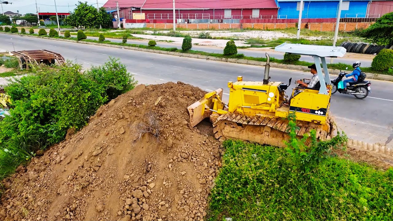 Good bulldozer operator shows excellent skill pushing soil filling land with dump trucks